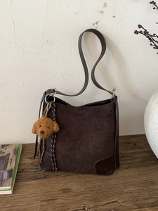 Deep brown matte suede tote bag with dog charm on wooden table, vintage aesthetic