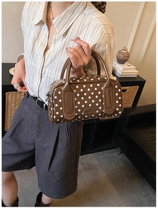 Detail of a brown polka dot Boston bag with leather handles and brand logo