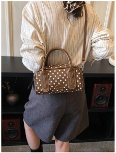 Macro detail of brown polka dot handbag featuring a retro logo and smooth PU leather finish