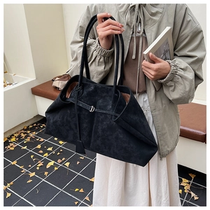 Detail of a large black suede tote bag with brown interior and long shoulder straps