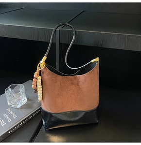 Détail du sac cabas en daim mat avec breloque en perles de bois et contraste en cuir