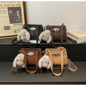 Close-up of four minimalist shoulder bags in various colors with cute rabbit pendants