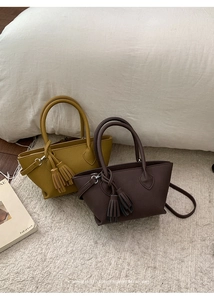 Detail of minimalist trapezoid handbags with lychee texture and decorative tassels