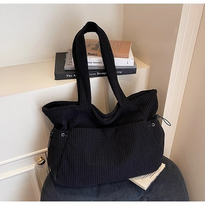 Detail of black corduroy tote bag showing vertical texture and side drawstring feature