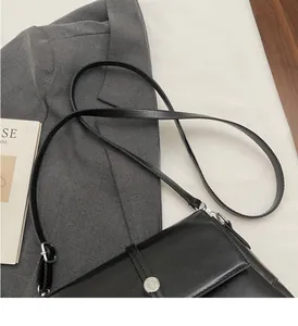 Détail de la longue bandoulière réglable et boucle argentée sur le sac bandoulière noir vintage