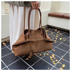 Macro shot of brown suede tote bag with slim decorative straps and metal buckles