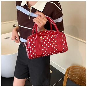 Close-up of a red polka dot Boston handbag with a luxury embossed logo and twin handles