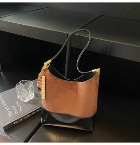 Détail du sac seau en daim marron avec bordure en cuir noir et breloque en perles