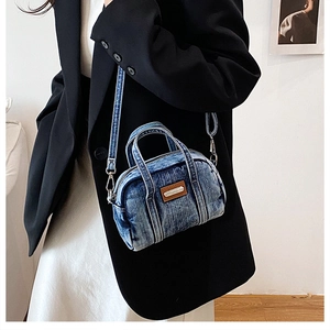 Detail view of mini washed blue denim boston bag with brown leather patch and crossbody strap