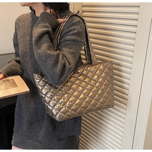 Detailed view of the large quilted tote bag in metallic champagne gold finish on shoulder