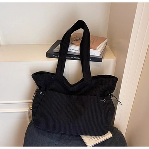 Detail of black corduroy tote bag showing ribbed texture and side drawstring design