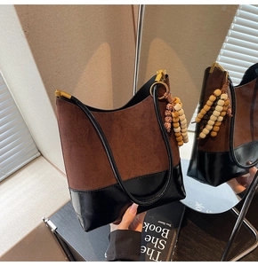 Détail du sac cabas bicolore en daim marron et cuir noir avec pendentif à perles bohème