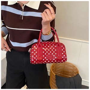 Detail of red patent leather Boston bag with white polka dots and dual top handles