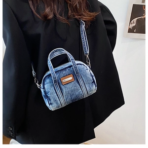 Detail of blue washed denim mini pillow bag with adjustable crossbody strap on model