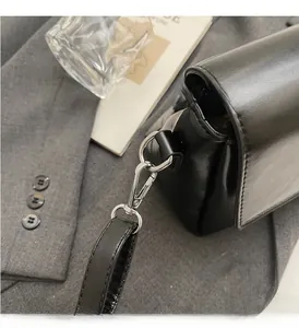 Détails des crochets métalliques argentés et de la bandoulière amovible d'un sac en cuir noir