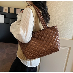 Close-up of glossy brown quilted tote bag with diamond pattern and padded shoulder strap