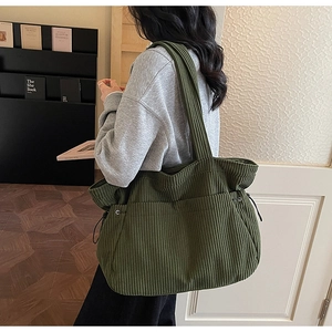 Detail of olive green corduroy tote bag showing soft ribbed texture and drawstring side
