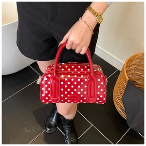 Detail view of red polka dot Boston handbag with glossy finish and logo engraving