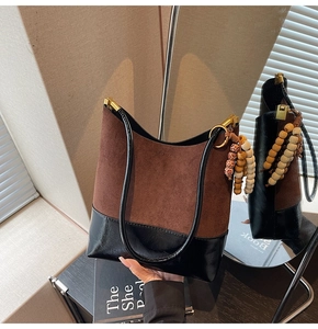 Détail du sac cabas contrasté en suédine avec pompon en perles de bois bohème