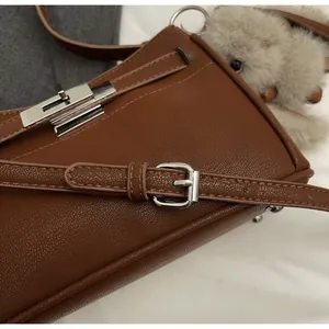 Detail of brown litchi pattern leather bag showing silver metal turn-lock and strap