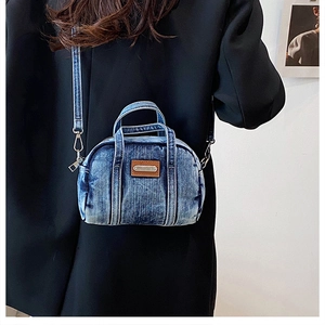 Detail of vintage blue denim bowling handbag with leather patch and detachable strap