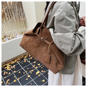 Detail of vintage brown leather tote bag showing buckle straps and smooth matte texture