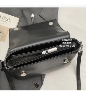 Détail du sac bandoulière en cuir noir mat montrant la fermeture éclair et magnétique