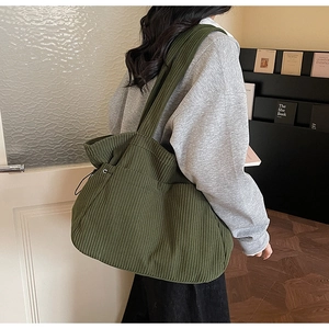 Olive green corduroy tote bag showing side drawstring detail and wide shoulder strap