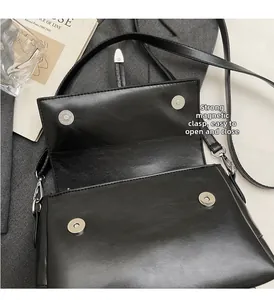 Gros plan d'un sac en similicuir noir montrant le fermoir magnétique et l'intérieur