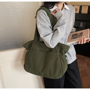 Detail of dark green corduroy tote bag showing vertical ribbed texture and drawstring side