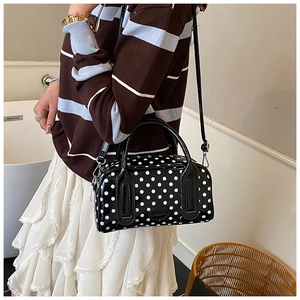 Polka dot handbag shown with shoulder strap on a model wearing a striped sweater