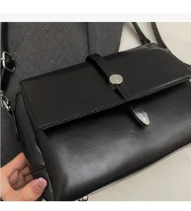 Vue détaillée du sac bandoulière noir minimaliste avec boucle métallique circulaire