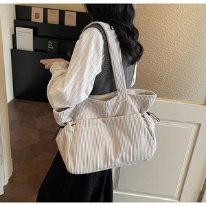 Detail of cream corduroy tote bag with side drawstring and pockets on a model