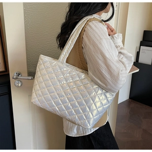 Detail view of white quilted tote bag with metallic gloss finish and wide shoulder strap