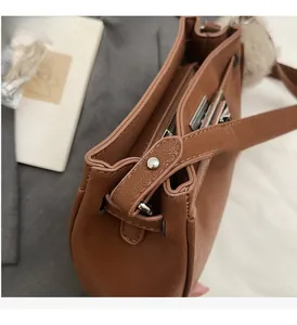 Detail of brown lychee grain leather shoulder bag with zipper and plush ball charm