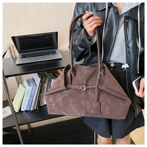 Macro shot of brown faux leather tote with buckle detail and side fold structure
