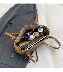 Detail view of the spacious inner compartments and gold buckle on a retro brown tote bag
