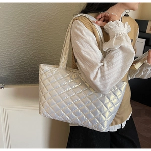 Silver quilted tote bag with diamond stitching pattern shown on a female model shoulder