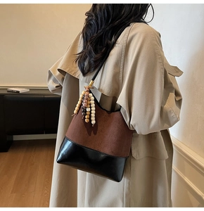 Retro patchwork tote bag with wooden beads and tassels shown on a beige coat