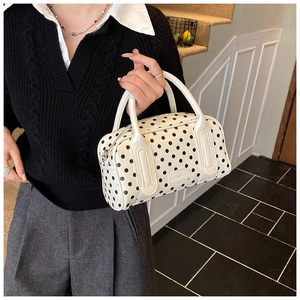 Detailed view of the Boston style handbag with black polka dots and silver zipper detail