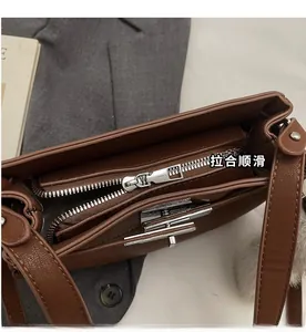 Detail view of the brown leather bag interior with silver zipper and rotary buckle