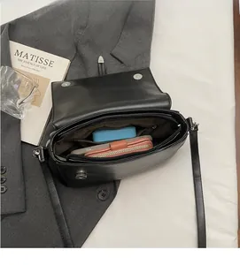Vue intérieure du sac bandoulière en cuir noir avec grand compartiment et poche zippée