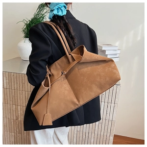 Detail view of large brown suede tote bag with leather straps and side tassel charm