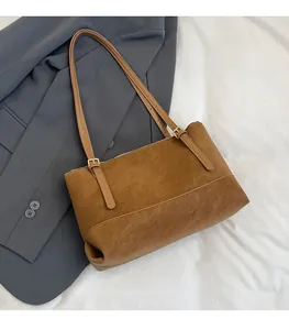 Detail of adjustable strap and stitching on a vintage brown tote bag over a blazer