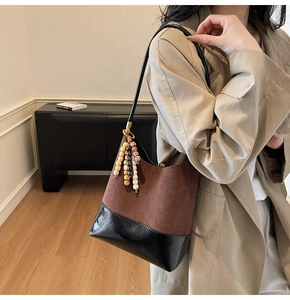 Détail du sac seau en daim avec perles décoratives en bois et finitions en cuir noir