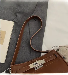 Detail of brown litchi grain leather bag with silver twist lock and plush charm accessory