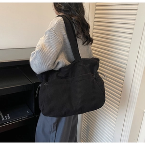 Detail view of black corduroy tote bag featuring adjustable drawstring and soft texture