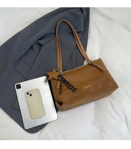 Brown leather tote bag capacity comparison with tablet and smartphone reference