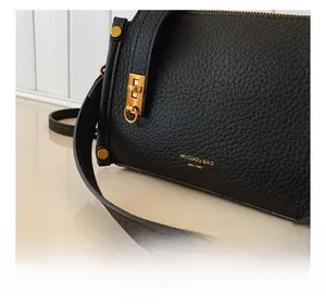 Detail der schwarzen Handtasche aus Narbenleder mit goldenem Drehverschluss und MK-1987 Logo