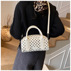 Detail of white polka dot Boston bag with metal logo plate and smooth double handles